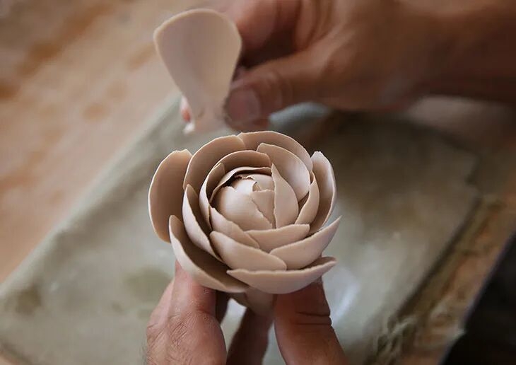 Master artisan sculpting a delicate porcelain flower through 36 meticulous steps - Aromamandala Heritage Craft.