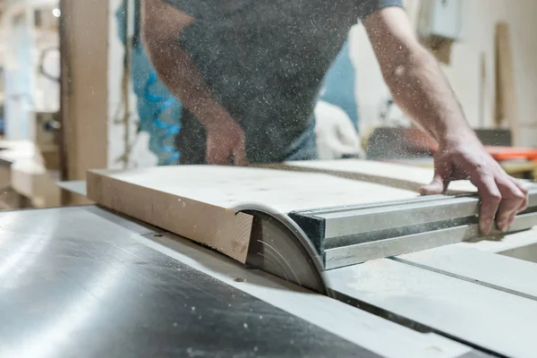 Cutting wooden board on sliding table saw