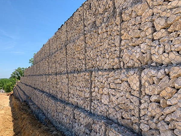 Stone-filled gabion basket for retaining wall construction