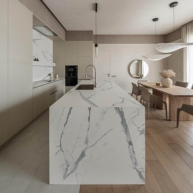 White quartz island countertop with grey veining and white kitchen cabinets